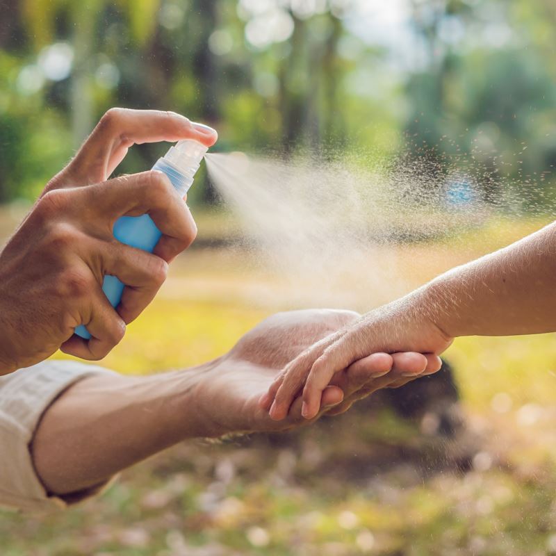 Guy Spraying His Arm With Insect Repellent