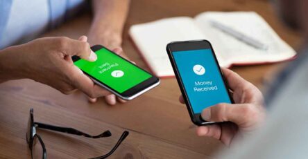 Man and woman holding smartphone and making payment transaction. Smart phone screen displaying payment sent and money received message after transaction.