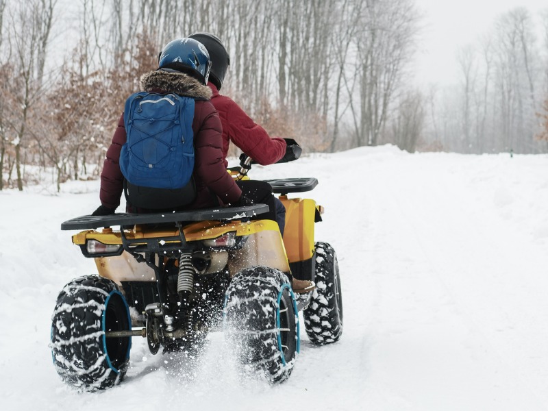 Two People Riding On An Atv Through The Snow