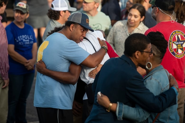 Two Pairs Of People Kissing Among A Larger Crowd.