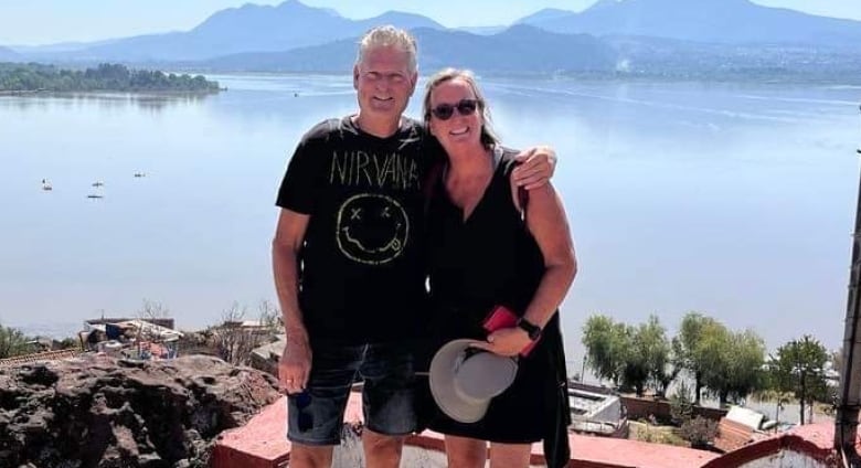 Sylvie Gadbois Poses For A Photo With Her Husband In Front Of A Landscape In Mexico.