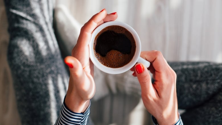 Hands hold a cup of coffee.